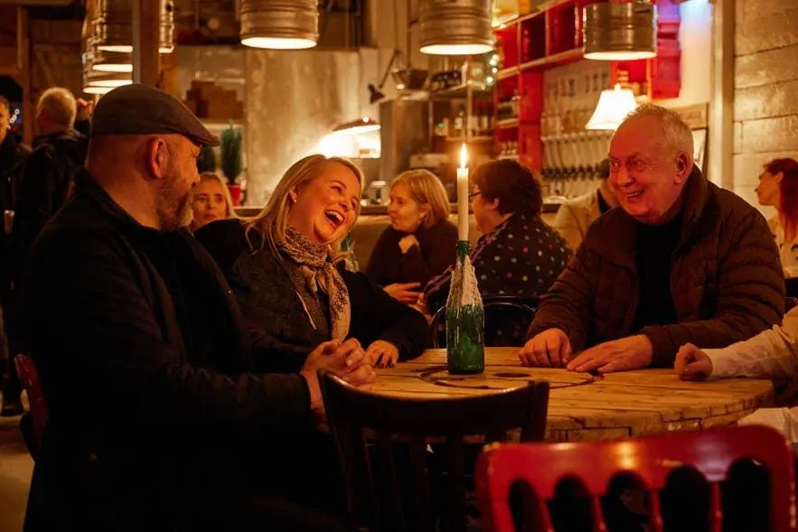 Friends laughing around a table in a warmly lit Reykjavík bar